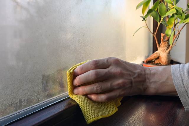 Person wiping condensation off window