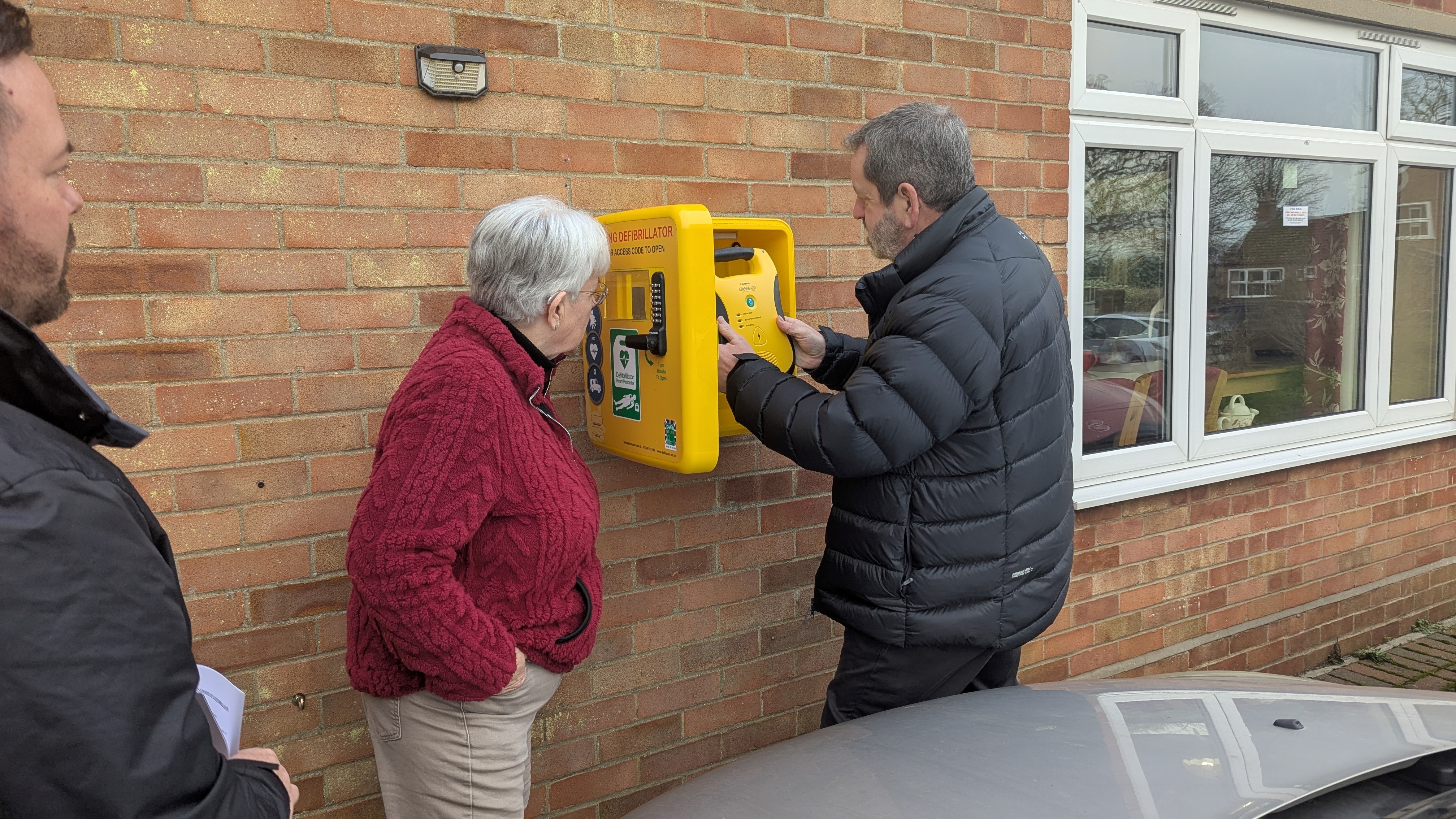 Tom McClenaghan and Jackie Hargreaves install the defibrillator in its storage case outside the community centre in Lamberts Close in Weasenham St Peter