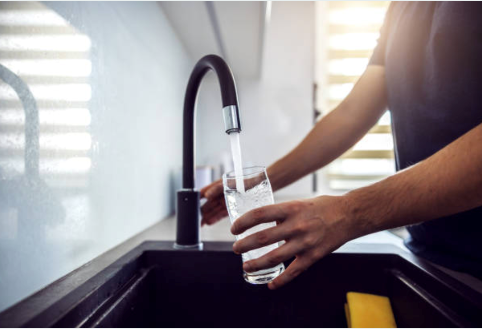 Image of person filling up a glass of water from the tap