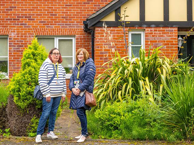 Two people standing outside house